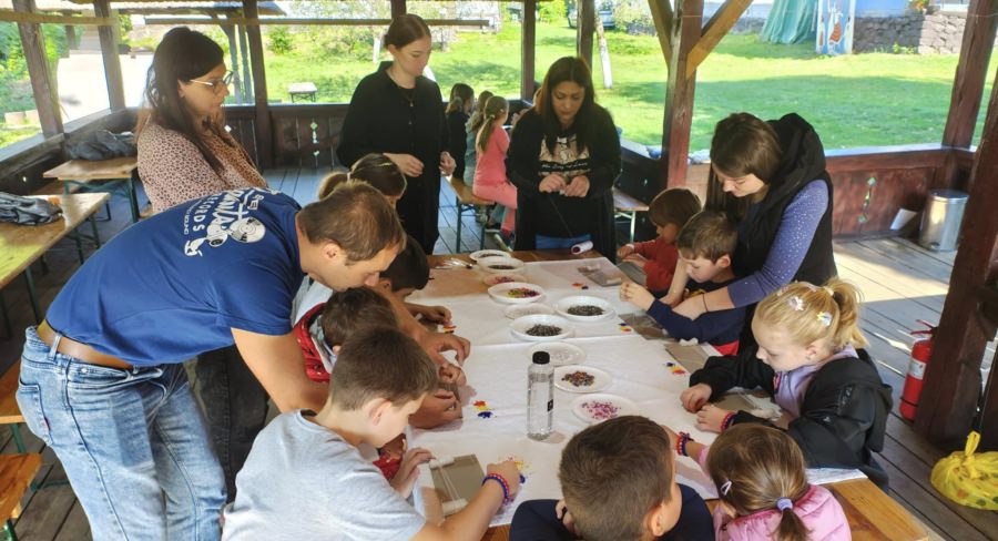 Meșterii populari Ana Mețenti și Viorelia Butcure, alături de copiii prezenți la atelierele de vacanță de la Muzeul Satului Baia Mare